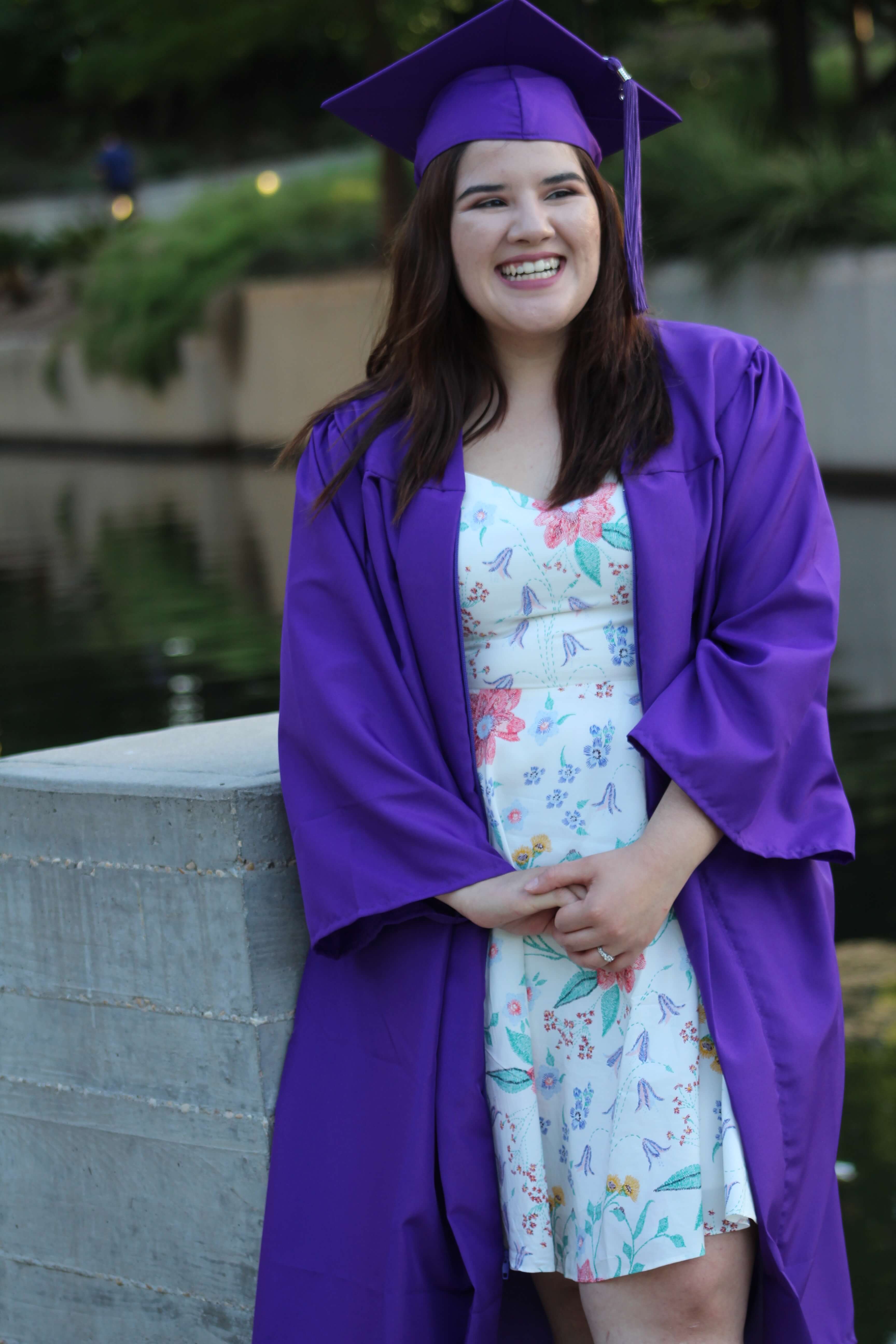 Vanessa Limon, a 2019 scholarship winner, wears a floral dress with a blue graduation gown and cap.