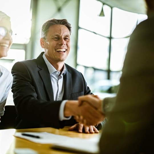 smiling business man shaking hands with another business person