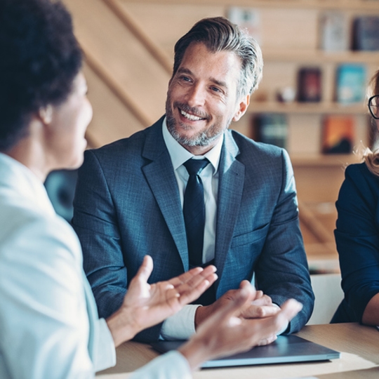 a man and women sitting smiling at another women who is talking to them