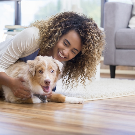 Women smiling on the floor holding her pupply who is brown and fluffy