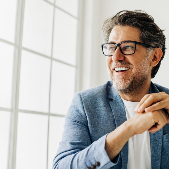 A man smiling in a suit and glasses