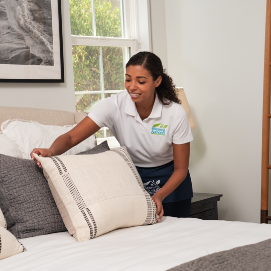 Women fluffing pillow while smiling