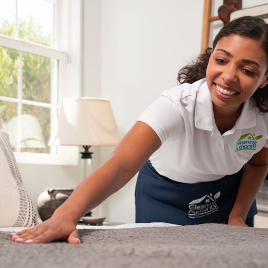 A women smiling with a white shirt touching the bed