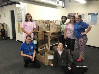 The TCA Norwell team stands in their office with donations collected for a local charity.
