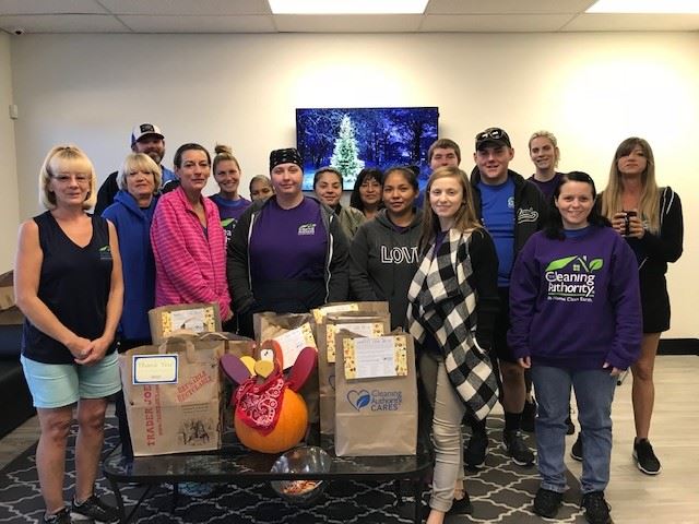 The TCA Phoenix team stands in their office with donations collected for a local charity.